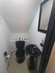 een badkamer met een zwart toilet en een wastafel bij Cerca al centro con parqueo GRATIS - 2 habitaciones in Popayan