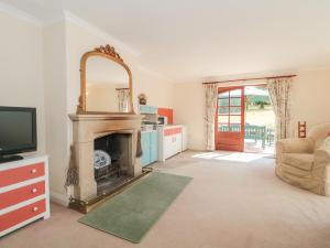 a living room with a fireplace and a television at Rhode Acres in Sturminster Newton