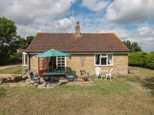 a small brick house with an umbrella and chairs at Rhode Acres in Sturminster Newton
