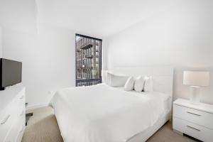 a white bedroom with a white bed and a tv at Global Luxury Suites at Reston Town Center in Reston
