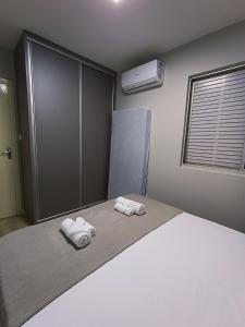 a bedroom with a bed with towels on it at Apto amplo Aconchegante 3Qts, TV 65, Ar Cond Ótima localização in Maringá