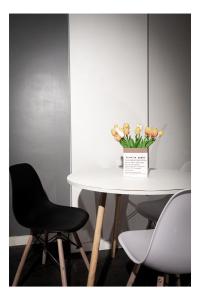 a table with a black chair and a vase of flowers at Central Perk Apartments-Antwerp in Antwerp