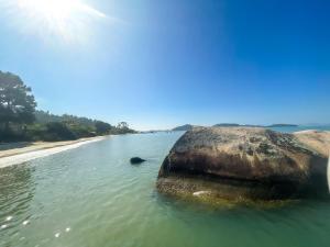 a rock in the water next to a beach at Pousada Recanto das Flores in Governador Celso Ramos
