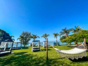 a hammock in a park with the ocean in the background at Pousada Recanto das Flores in Governador Celso Ramos