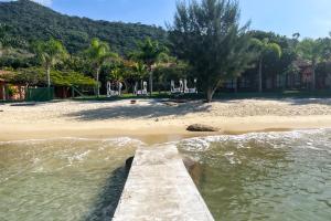 a dock in the water next to a beach at Pousada Recanto das Flores in Governador Celso Ramos