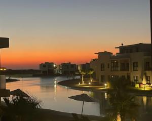 a sunset over a pool with umbrellas and buildings at Lovely chalet 4- bedroom directly on the lagoon in El Alamein