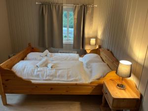 Cama grande de madera con sábanas blancas y ventana en Nørdre-Repp en Boverdalen