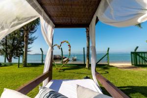 a bed in a tent with the beach in the background at Pousada Recanto das Flores in Governador Celso Ramos