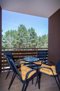 einen Balkon mit einem Tisch, Stühlen und Bäumen in der Unterkunft Vila Pekovic Blue-Apartman PAMA in Zlatibor