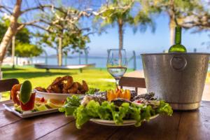 a table with a plate of food and a glass of wine at Pousada Recanto das Flores in Governador Celso Ramos