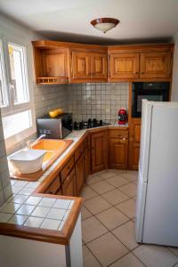 cocina con armarios de madera y nevera blanca en Maison chaleureuse avec exterieur près de la ville, en Lafox