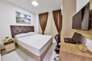 a bedroom with a bed and a desk with a laptop at Hotel Aracaju Suites in Aracaju
