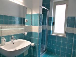 un bagno piastrellato blu con lavandino e finestra di Donna Ester - Discover Cilento a Pisciotta