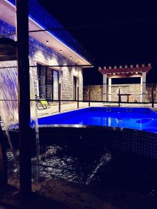- une piscine en face d'une maison la nuit dans l'établissement Alshafaq chalet, à Al ‘Aqar