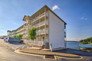 a apartment building with a parking lot next to the water at Top-Floor Lands End Corner Unit with Resort Perks! in Osage Beach