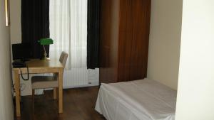 a bedroom with a desk and a bed and a desk with a lamp at Pension Schottentor in Vienna