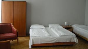 a bedroom with two beds and a red chair at Pension Schottentor in Vienna
