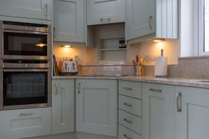 una cucina bianca con armadietti e elettrodomestici bianchi di The Grove - Bude Cornwall a Bude