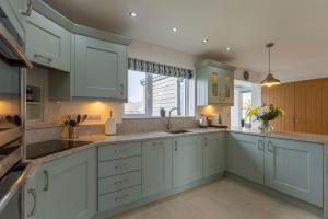 a kitchen with white cabinets and a large window at The Grove - Bude Cornwall in Bude