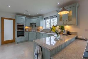 eine Küche mit blauen Schränken und einer Vase mit Blumen auf der Theke in der Unterkunft The Grove - Bude Cornwall in Bude