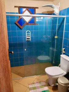 a blue tiled bathroom with a toilet and a shower at Aconchego da Raquel in Itaúnas