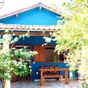 a blue house with a wooden table in front of it at Aconchego da Raquel in Itaúnas
