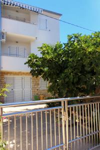 a fence in front of a building with a tree at Apartments by the sea Kosljun, Pag - 3321 in Košljun
