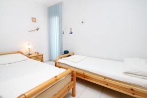 two twin beds in a room with a window at Apartments by the sea Kosljun, Pag - 3321 in Košljun