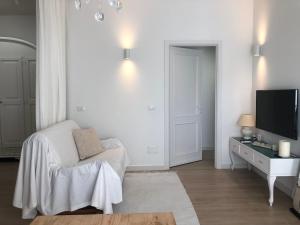 a white living room with a white couch and a tv at Casa giardino santadi in Santadi
