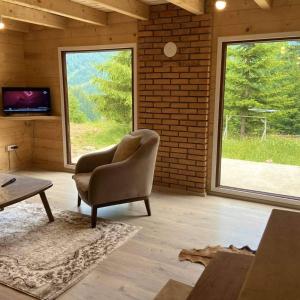 uma sala de estar com uma cadeira, uma televisão e janelas em Villat Shkreli Relax em Pec
