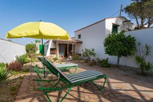 two lawn chairs and an umbrella on a patio at Casa Rural La Capellania in Granadilla de Abona
