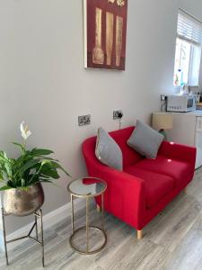un divano rosso in un soggiorno con una pianta di Hugo Mews Bright Studio Apartment a Bray