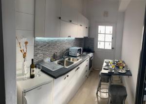 una cucina con armadi bianchi, lavandino e tavolo di Nikilein's House, διαμέρισμα 150μ απο την παραλία a Roda