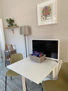 uma sala de estar com uma mesa branca e uma televisão em Hugo Mews Bright Studio Apartment em Bray