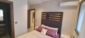 een kamer met een bed met paarse kussens erop bij Al Anouar Résidence in Kenitra