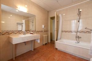a bathroom with a sink and a tub and a mirror at Hotel Norte y Londres in Burgos
