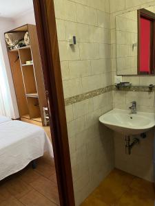 Pensión A Pedra في دومبريا: حمام مع حوض بجانب سرير