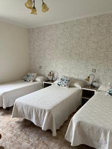 um quarto com três camas e uma parede com papel de parede em Pensión A Pedra em Dumbría