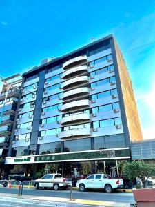 un gran edificio con coches estacionados frente a él en Garden Park Hotel en San Miguel de Tucumán