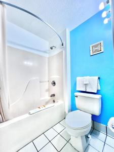 y baño con paredes azules, aseo y bañera. en Bayou Inn & Suites, en Bayou La Batre