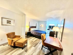 Bayou La BatreにあるBayou Inn & Suitesのベッド、デスク、椅子が備わるホテルルームです。