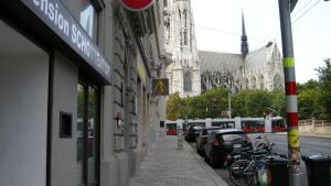 una strada con auto parcheggiate e un edificio con cattedrale di Pension Schottentor a Vienna