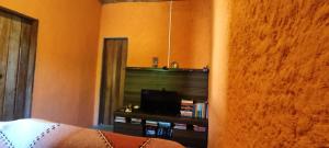 uma sala de estar com uma televisão e um sofá em Toca dos Prazeres Estalagem Bistrot em Igatu