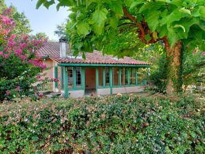 a small house with green trim and pink flowers at villa 8 personnes ô Mes Anges in Saint-Julien-en-Born
