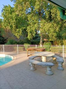 un patio con una mesa y un banco junto a una piscina en villa 8 personnes ô Mes Anges en Saint-Julien-en-Born