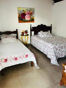 a bedroom with two beds and a painting on the wall at Pousada Dona Terezinha in Formiga