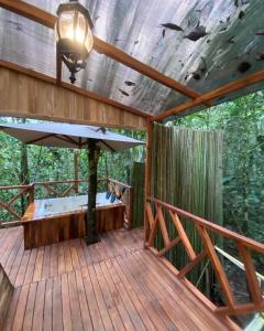 eine Holzterrasse mit einem Bett und einem großen Sonnenschirm in der Unterkunft ECO HOTEL RIO DE ORO in San Rafael