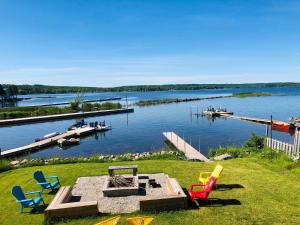 een groep stoelen op het gras naast een steiger bij Peaceful Waterfront Cottage on Georgian Bay in Victoria Harbour