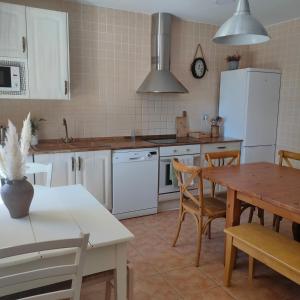 a kitchen with a table and a white refrigerator at Casa Rural Torre Gil in Alcañiz