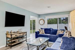 a living room with a blue couch and a tv at Charming home near beach & golf with central AC & patio - dog-friendly in Palm Coast